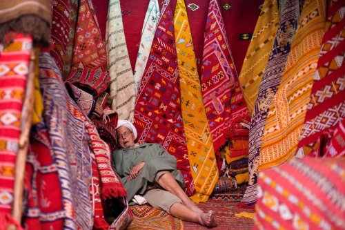 A sleeping carpet saleman in busy Morocco.
