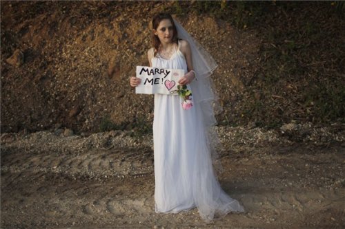 Israeli Hallel Goldman 13 wears a wedding dress as she holds a sign for