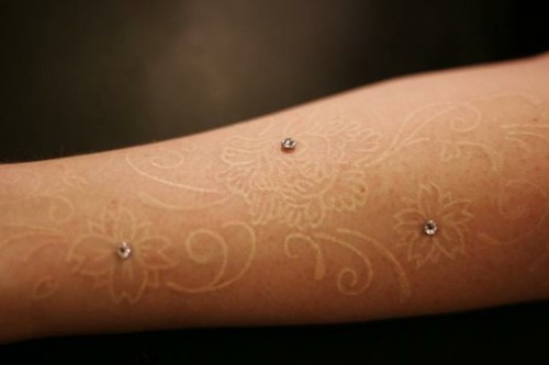 floral white ink tattoo with dermal anchor piercings