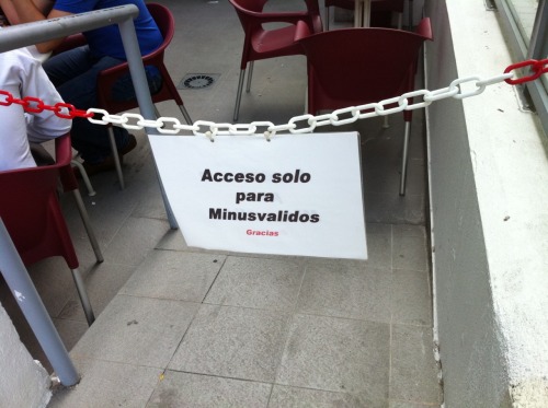 Rampa que facilita el acceso a una terraza de una cafetería cerrada con una cadena y un cartel 'Acceso solo para Minusvalidos. Gracias'