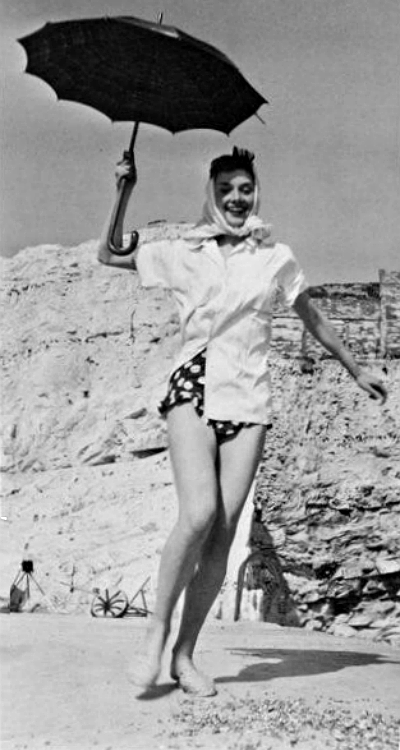 Audrey Hepburn in polka dot bikini bottoms holding an umbrella on the beach